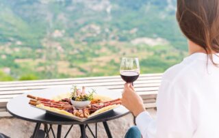 Woman enjoying wine and local food platter with mountain view in Montenegro