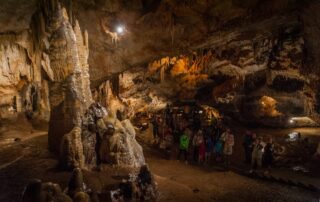 Large stalagmite formations with tour group inside Lipa Cave, Cetinje Montenegro